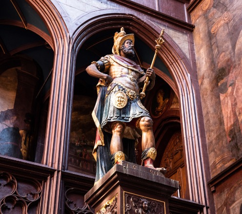 Die Statue von Lucius Munatius Plancus im Rathaushof in staatsmännischer Pose von unten fotografiert. In seiner Linken hält Munatius ein Zepter, die rechte Hand stützt er auf die Hüfte auf.
